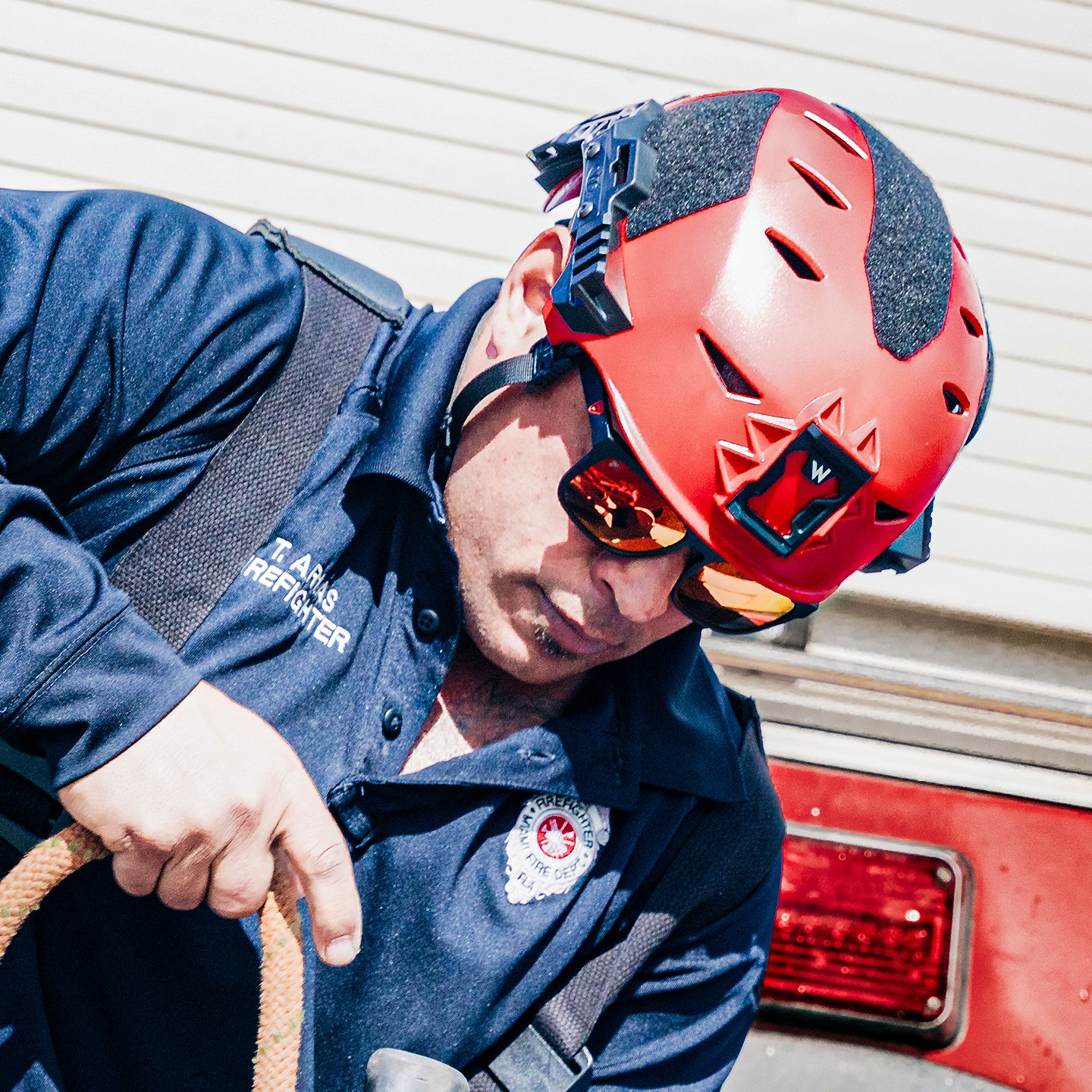 Firefighter leaning off a rig wearing Frontline Optics sunglasses